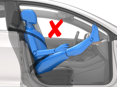 a person sitting with their legs on the dashboard and a red x