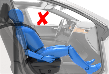 Person sitting in car seat incorrectly with hips at the front of the seat cushion