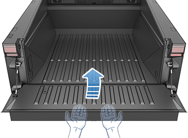The cargo bed with the tailgate open and a pair of hands positioned under the tailgate to demonstrate how to close it