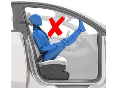 a person sitting with their legs on the dashboard and a red x